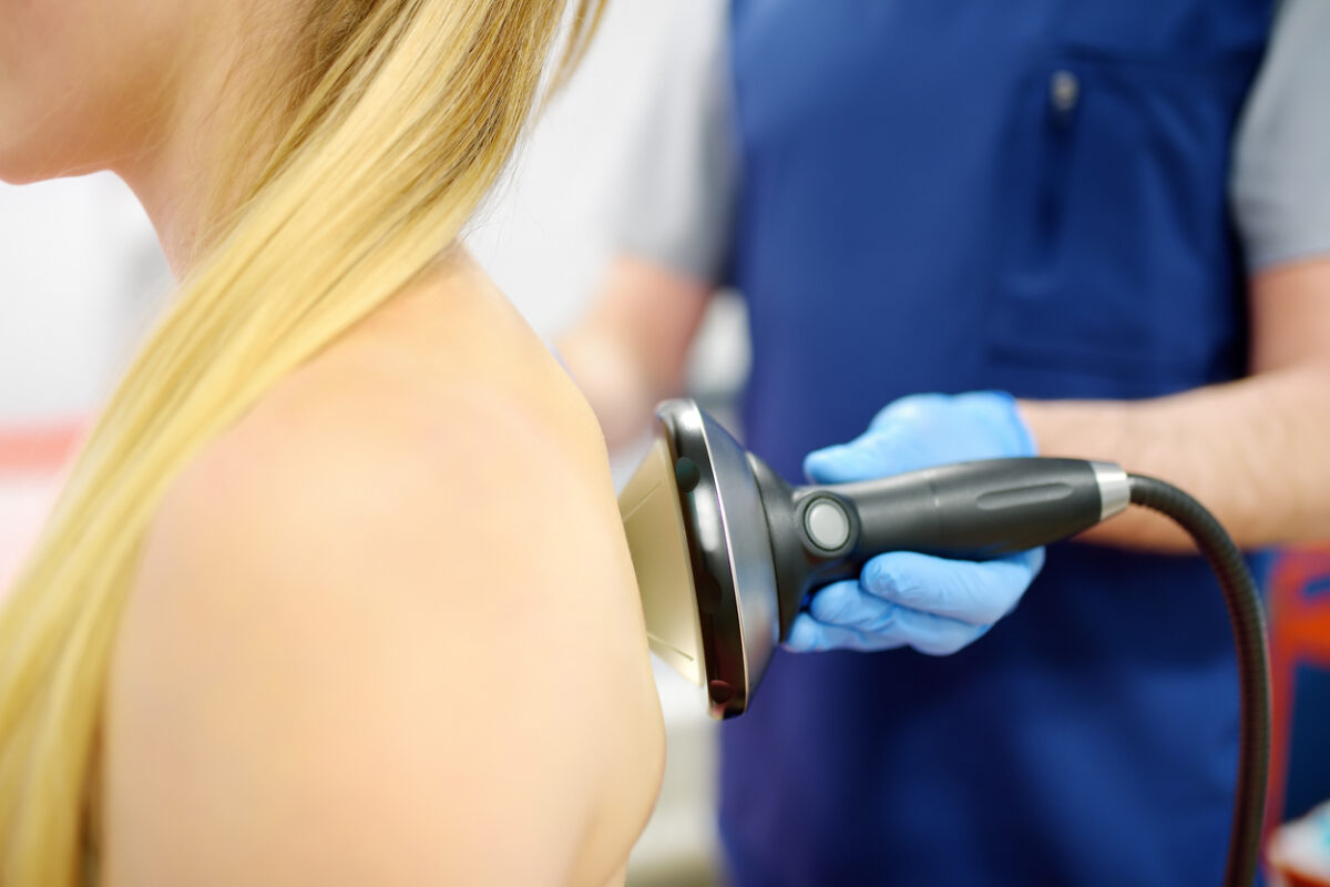 Close-up of focused shockwave therapy being applied to neck and back muscles in an evidence-based chiropractic clinic.