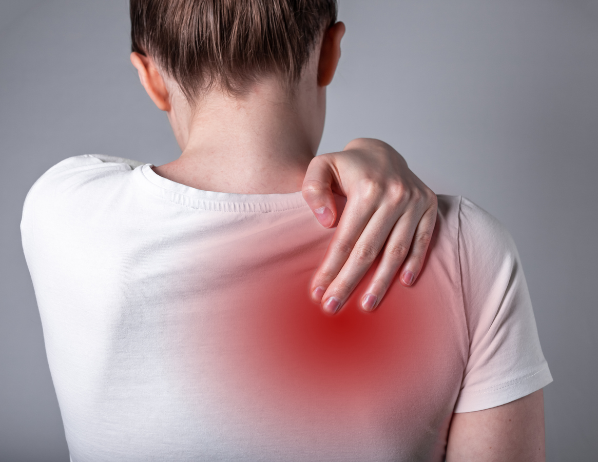 Woman holding shoulder blade in pain with red trigger point highlight.