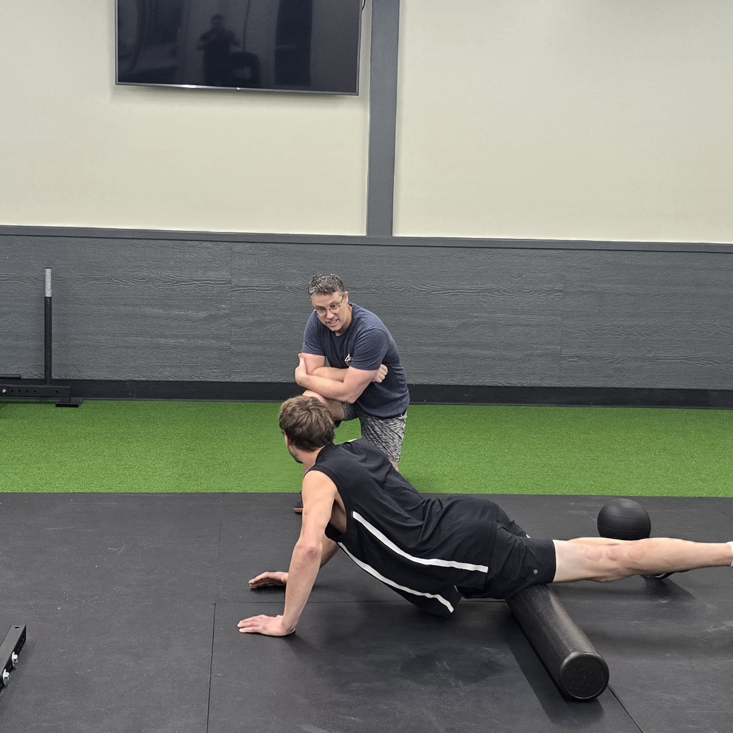 Coach Chris guiding a client foam rolling before a strength workout at Ascent Health & Performance